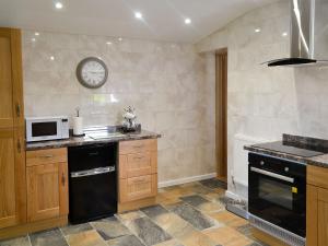 a kitchen with a stove and a microwave at Penrhos Bach in Llanerchymedd +9 photos