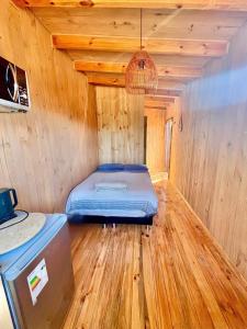 a bed in a room with a wooden floor at Tiny House Pangal in Pichilemu