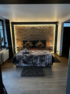 a room with a bed with a brick wall at Suite Tino - Jacuzzi privé, cabine infrarouge & vue in Verviers +174 photos