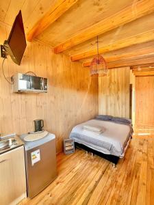 a bedroom with a bed in a wooden cabin at Tiny House Pangal in Pichilemu