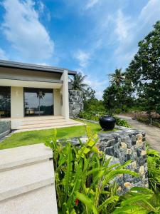 a house with a stone retaining wall and a garden at Hansa Villa in Weligama