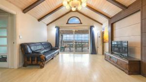 a living room with a leather couch and a tv at Ganghwa Daeun pension in Incheon