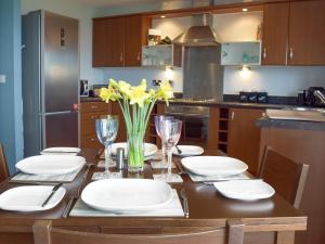 a kitchen with a table with white plates and yellow flowers at Gower Sunset Views in Llanelli