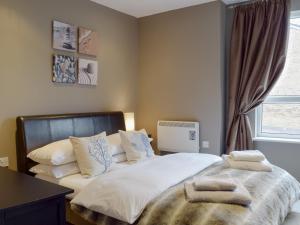 a bedroom with a bed with white sheets and pillows at Gower Sunset Views in Llanelli