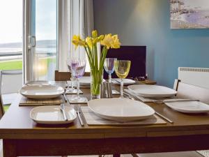 a table with plates and glasses and a vase of flowers at Gower Sunset Views in Llanelli
