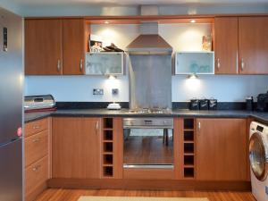 a kitchen with wooden cabinets and a stove top oven at Gower Sunset Views in Llanelli +4 photos