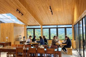 a group of people sitting at tables in a restaurant at Cozy Hostel and Tours in Ha Giang