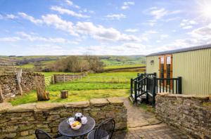 a patio with a table and chairs and a stone wall at Finest Retreats - Weardale Shepherds Hut in Bishop Auckland