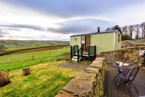 a tiny house with a table and a stone wall at Finest Retreats - Weardale Shepherds Hut in Bishop Auckland +9 photos