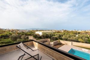 a balcony with two chairs and a swimming pool at Golden Silence in Platanias