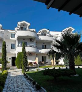 a large white building with a palm tree in front of it at Resort Comfort - Long Beach in Ulcinj