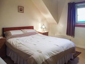 a bedroom with a large white bed with a window at Tigh Mairi in Tarbert