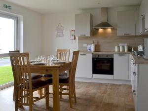 a kitchen with a wooden table and chairs and a kitchen with a stove at Rockworks Chalets No2 - Uk7041 in Saint Marys
