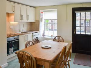 a kitchen with a wooden table and some chairs at 7 Quarrymans Cottage in Wadebridge