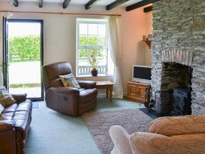 a living room with a couch and a stone fireplace at 7 Quarrymans Cottage in Wadebridge