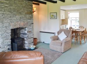 a living room with a stone fireplace and a chair at 7 Quarrymans Cottage in Wadebridge