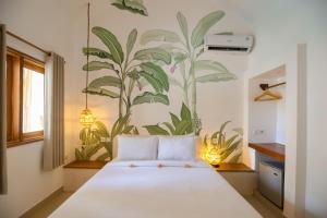 a bedroom with a large white bed with a mural on the wall at Green Banana in Gili Trawangan