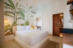 a bedroom with a white bed with a plant mural on the wall at Green Banana in Gili Trawangan