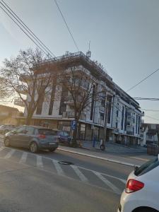 a building on a street with cars parked in front of it at For You in Vrnjci
