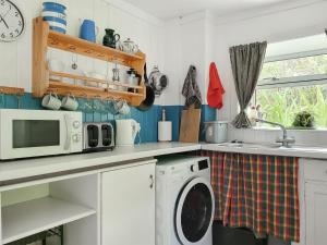 a kitchen with a washing machine and a microwave at Garradh An Fhasaich in Glendale
