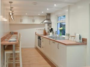 a kitchen with white cabinets and a wooden counter top at Snowdrop Cottage in Fishguard
