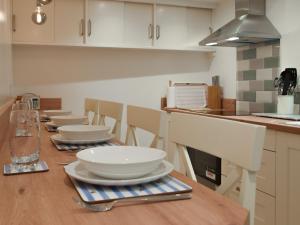 a kitchen with a wooden table with white dishes on it at Snowdrop Cottage in Fishguard +16 photos