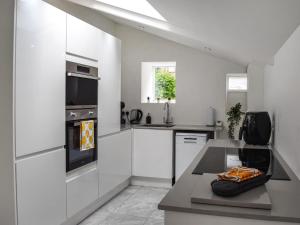 a kitchen with white cabinets and a stove top oven at Ye Olde Mottram Chip Shop in Glossop +9 photos
