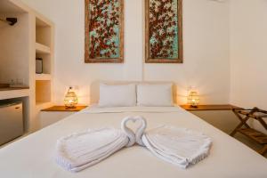 a white bed with a heart shaped towel on it at Green Banana in Gili Trawangan