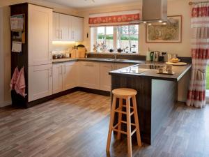 a kitchen with white cabinets and a bar with a stool at Grant Crescent in Dornoch