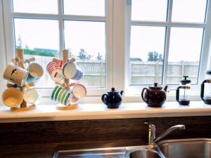 a kitchen counter with cups and a sink and windows at Grant Crescent in Dornoch