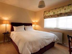 a bedroom with a large white bed with a window at Grant Crescent in Dornoch +9 photos