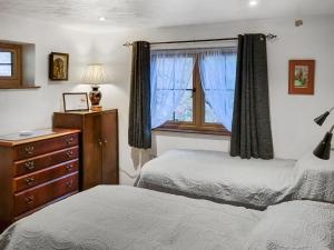 a bedroom with two beds and a dresser and a window at The Glen in Devils Bridge