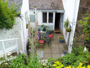 a small patio with a table and chairs and flowers at Ivybank Cottage in Lamlash