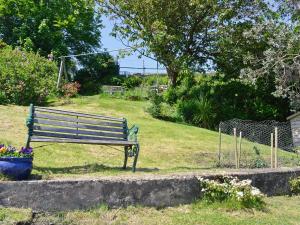 a park bench sitting in the grass next to a field at Ivybank Cottage in Lamlash
