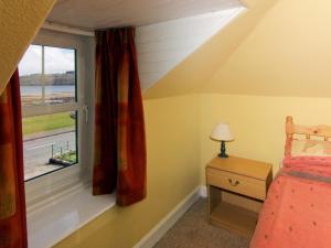 a bedroom with a bed and a window at Ivybank Cottage in Lamlash