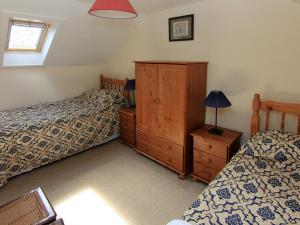 a bedroom with two twin beds and a dresser and a bed sqor at Ivybank Cottage in Lamlash