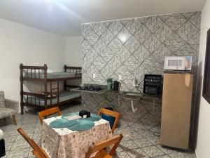 a kitchen with a table with a microwave and a refrigerator at Kitnet Estrela do Mar in Peruíbe
