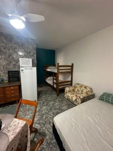 a room with a bed and a refrigerator and a chair at Kitnet Estrela do Mar in Peruíbe