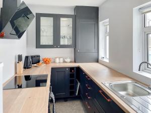 a kitchen with black cabinets and a sink at April House in Amble