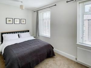 a white bedroom with a bed and two windows at April House in Amble