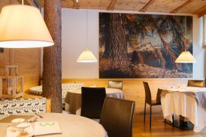 Un restaurante con mesas y sillas y un gran cuadro. en Maribel Hotel, en Madonna di Campiglio
