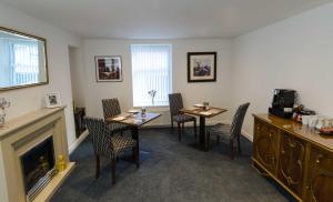a living room with two tables and chairs and a fireplace at Adderley House B&B in Pitlochry