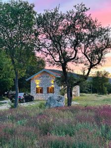 a stone house with a car parked in a field at Kostela Stone House in Stolac