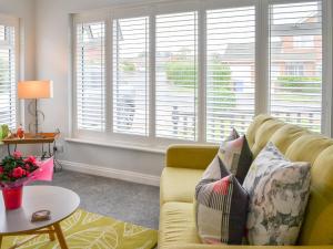 a living room with a yellow couch and windows at Poppys' Place in Sewerby