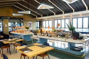 a restaurant with tables and chairs and windows at Azana Style Hotel Tulungagung in Tulungagung