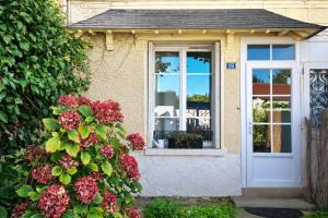 a house with a white door and flowers at Maison spacieuse au coeur du Centre - Plage à pied in Luc-sur-Mer