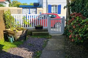 a white fence with a red car in a yard at Maison spacieuse au coeur du Centre - Plage à pied in Luc-sur-Mer