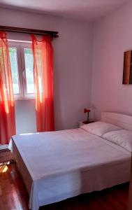 a bedroom with two beds and a window with red curtains at Robinson Josip in Bogomolje