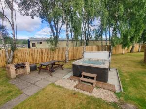 a backyard with a hot tub and a picnic table at Holly Lodge in Aviemore