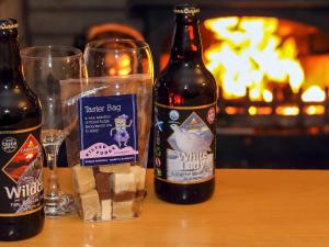 two bottles of beer sitting on a table with glasses at Holly Lodge in Aviemore